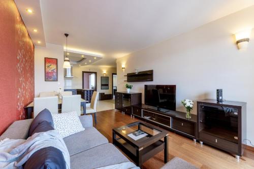 a living room with a couch and a tv at Apartamenty Bałtyckie - Bulwar Portowy - widok na port, centrum, najlepsza lokalizacja w Ustce in Ustka