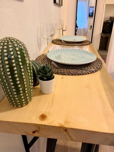 une table en bois avec deux assiettes et un cactus dans l'établissement Au ColbVert, à Lille