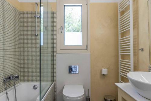 a bathroom with a sink and a toilet and a window at Villa Olive Grove Kefalonia in Ferendináta