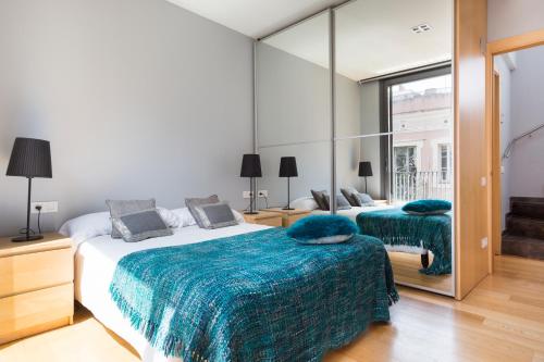 1 dormitorio con 2 camas y un espejo grande en Barcino Inversions - Bright Apartment in Gracia with shared Pool en Barcelona