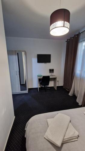 Habitación de hotel con cama, escritorio y TV. en Casa Soficu en Iaşi