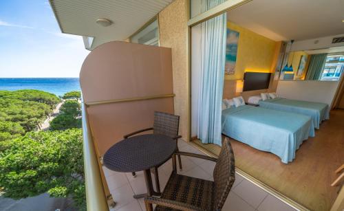 Habitación de hotel con cama, mesa y sillas en Hotel Blaumar, en Blanes