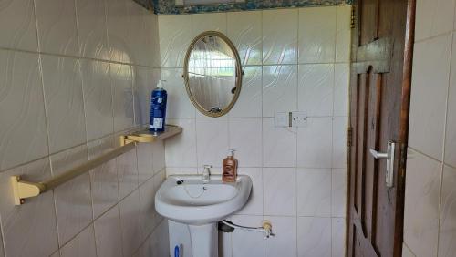 y baño con lavabo y espejo. en Tradewins Cottage, en Diani Beach