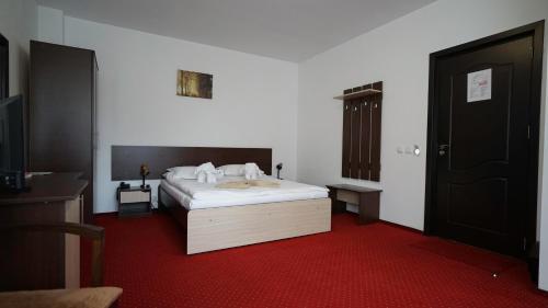 a bedroom with a white bed and a red carpet at Vila Trandafirul si Liliacul in Căciulata
