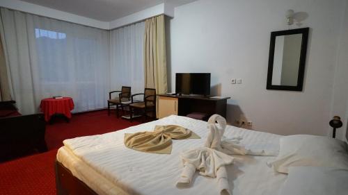 a hotel room with a bed with towels on it at Vila Trandafirul si Liliacul in Căciulata