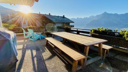 een houten tafel en stoelen op een balkon met de zon bij Fontanettaz V 007 - MOUNTAIN & VIEW apartment 8 pers in Veysonnaz