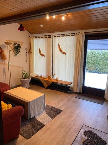 ein Wohnzimmer mit einem Tisch und einem großen Fenster in der Unterkunft Ferienhaus Feriendorf Kurort Bad Dürrheim in Bad Dürrheim