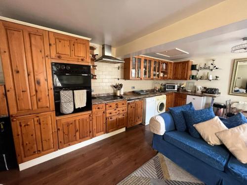 eine Küche mit Holzschränken und einem blauen Sofa in der Unterkunft 2 bedrooms Bell Cottage in Hoddesdon