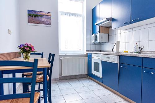 a kitchen with blue cabinets and a table with a vase of flowers at Haus Silko - FeWo in top Lage - 3 min zum Strand direkt am Kurpark in Warnemünde