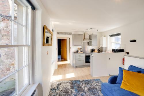 a living room with a blue couch and a kitchen at Little Edge: Bright and Modern Central Apartment in Berwick-Upon-Tweed