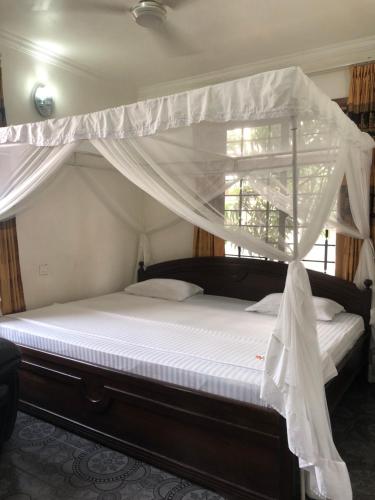 1 dormitorio con cama con dosel y cortinas blancas en Jambo hostel tz, en Dar es Salaam