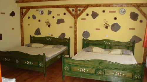 クルツィショアラにあるPensiunea Dealu Moriiのベッド2台 壁に岩を敷いた部屋