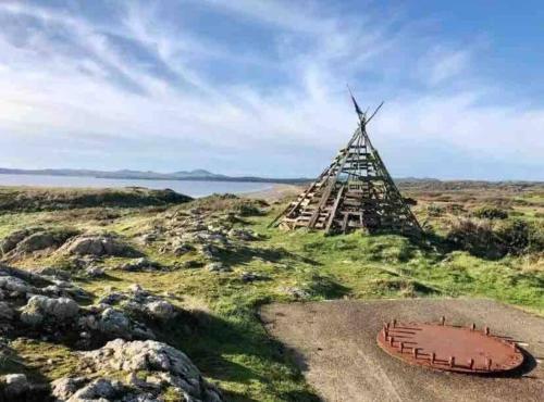 a windmill on a field with a body of water at Snowdonia View@puffin Lodges in Chwilog