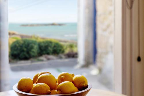 a bowl of oranges sitting on a table next to a window at Bijou Bolthole in Mousehole
