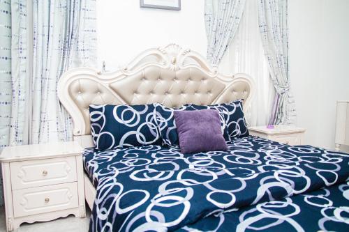 um quarto com uma cama branca e uma almofada roxa em The Serenity Villa em Lekki