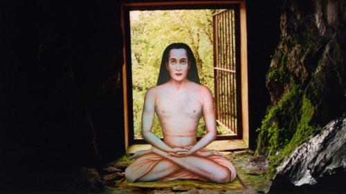 a shirtless man sitting in meditation in front of a window at Dwarahat Village Farmstay- Babaji's Cave in Dwārāhāt
