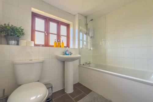 a bathroom with a toilet and a sink and a tub at Spacious-Rustic Cottage-Dog Friendly-w log burner in Worle
