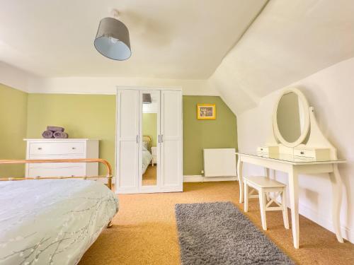 a bedroom with a bed and a dressing table and a mirror at Spacious-Rustic Cottage-Dog Friendly-w log burner in Worle