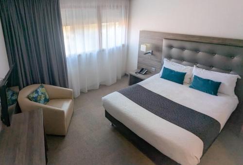 1 dormitorio con 1 cama grande y 1 silla en KYRIAD LYON EST - Genas Eurexpo, en Genas