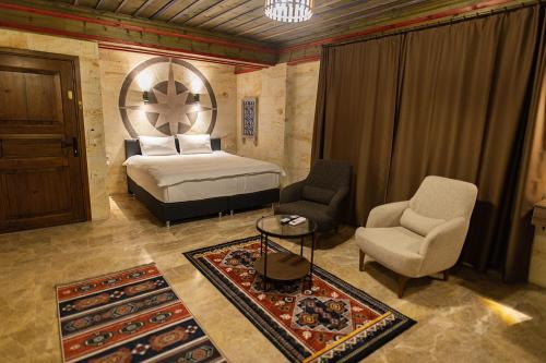 een slaapkamer met een bed en 2 stoelen en een tafel bij Uçhisar Premium in Nevsehir