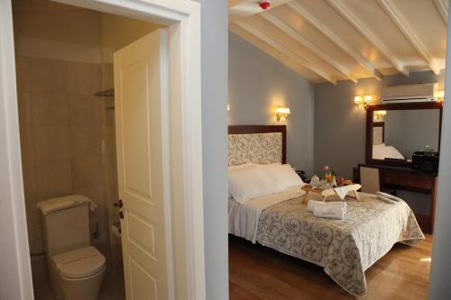 a bedroom with a bed and a bathroom with a toilet at Apollonion Palace in Ermoupoli