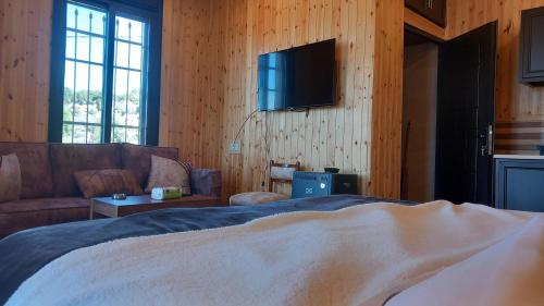 a bedroom with a bed and a couch and a television at Rosemary Huts in Ajloun