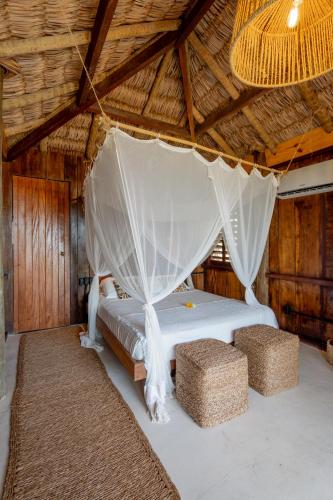 a bed in a straw hut with a mosquito net at Villa Mango in Icaraí