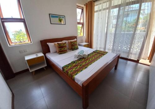 a bedroom with a bed in a room with windows at Haradali Suites 2 Bedroom Beach Apartment - Sultan Palace Beach Resort in Kilifi