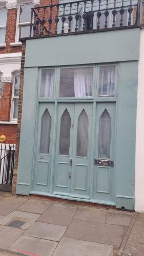 ein Gebäude mit blauen Türen und Fenstern an einer Straße in der Unterkunft Tranquil Haven: A Cozy Retreat for Four in London