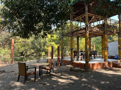 a wooden pavilion with chairs and a table and chairs at Brook Ville in Sasan Gir