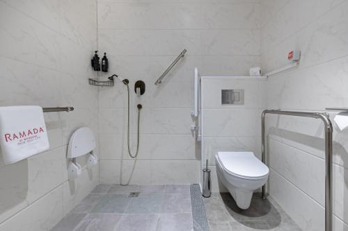 a white bathroom with a shower and a toilet at Ramada by Wyndham Tbilisi Old City in Tbilisi City