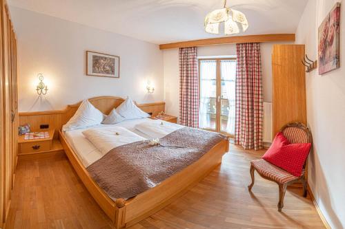 um quarto com uma cama grande e uma cadeira em Ferienwohnungen Zum Baur em Krün