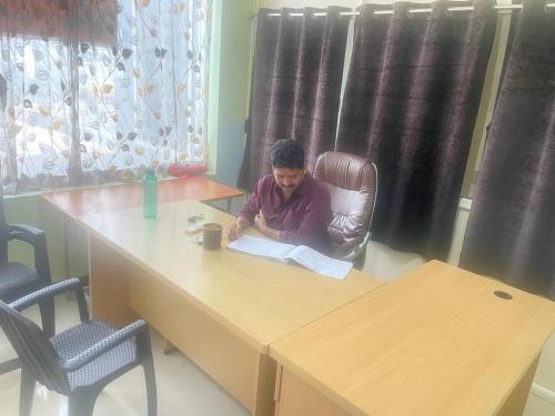 Een man aan een tafel die een boek leest. bij Adith Grand in Tirupati