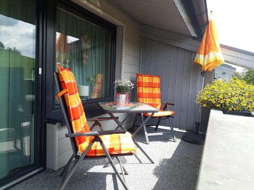 eine Terrasse mit 2 Stühlen, einem Tisch und einem Sonnenschirm in der Unterkunft Ferienwohnungen Bußmann in Herscheid