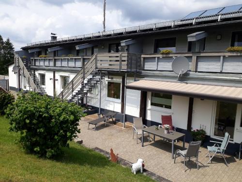 ein Gebäude mit einem Tisch und Stühlen davor in der Unterkunft Ferienwohnungen Bußmann in Herscheid