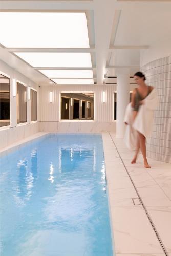 a woman walking next to a swimming pool at Villa-des-Prés in Paris