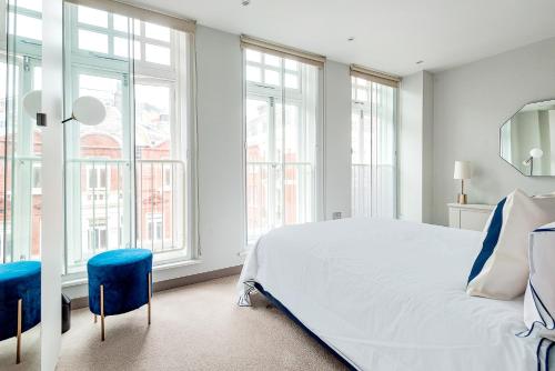 Arcore Premium Apartments: Mayfair في لندن: غرفة نوم بسرير ابيض كبير ونوافذ