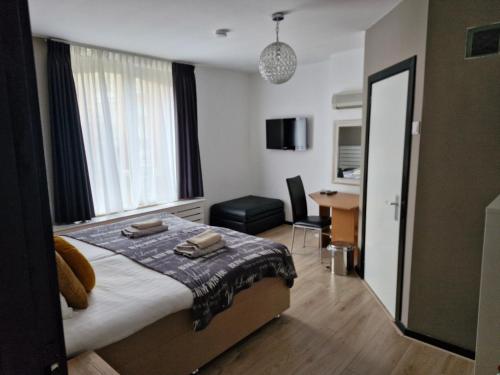 een slaapkamer met een bed, een bureau en een stoel bij Villa Insulinde in Scheveningen