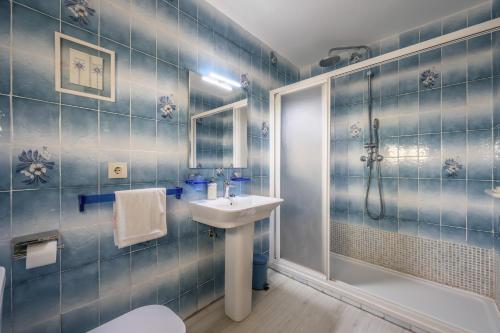 y baño de azulejos azules con lavabo y ducha. en CASA TURISTICA LA PARRA, en La Lastrilla