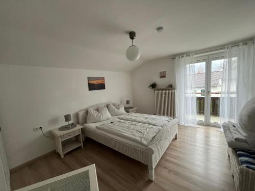 a white bedroom with a bed and a large window at Ferienwohnung am Chiemsee in Bernau am Chiemsee