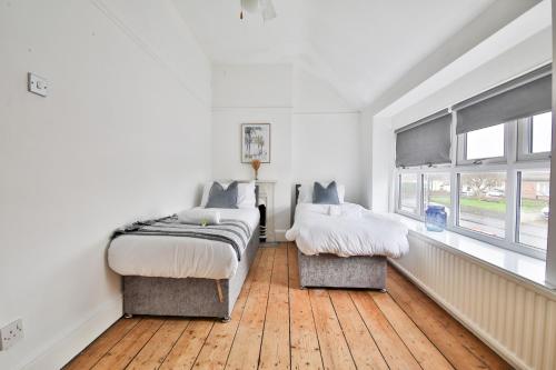 1 dormitorio con 2 camas y 2 ventanas en StayRight Homely 3 Bedroom House in Vibrant Whitchurch, en Cardiff