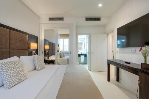 a white bedroom with a large bed and a desk at Hotel Saray in Granada