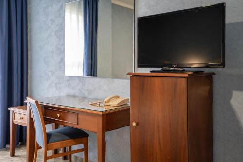 a hotel room with a desk with a television and a phone at Hotel Bartos in Almussafes