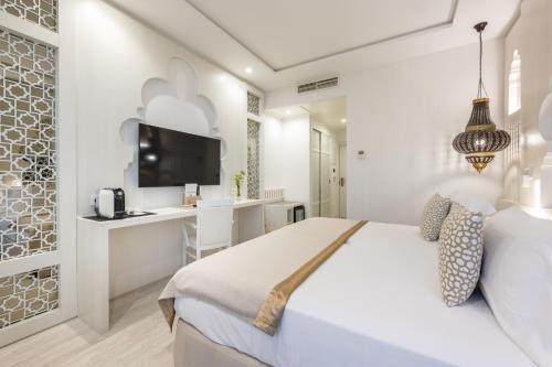 a white bedroom with a bed and a desk at Hotel Saray in Granada