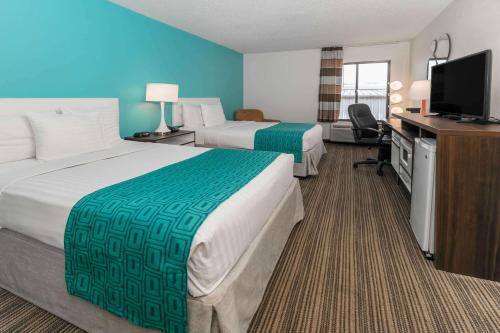 a hotel room with two beds and a flat screen tv at Howard Johnson by Wyndham Scott Lafayette in Scott