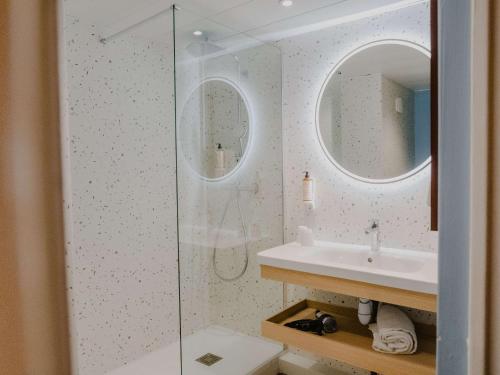 La salle de bains est pourvue d'un lavabo et d'une douche en verre. dans l'établissement Mercure Le Havre Centre Bassin Du Commerce, au Havre
