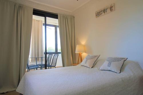 1 dormitorio con cama blanca y ventana en MARCOGDUR - Appartement pour 4 personnes à 100m de la plage situé aux Marines de Cogolin en Cogolin