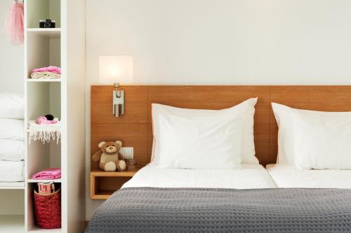 a bedroom with a bed with white sheets and a teddy bear at Sunwing Alcudia Beach in Alcudia