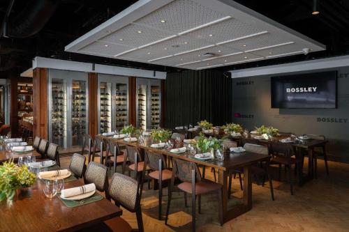 a dining room with tables and chairs and a tv at Rydges Melbourne in Melbourne