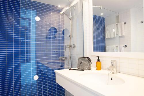 a blue tiled bathroom with a sink and a shower at Sunwing Alcudia Beach in Alcudia